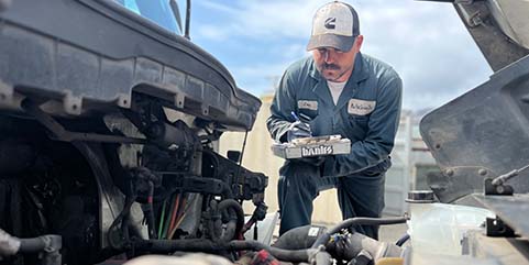 Mechanic performing fleet maintenance on a commercial truck.